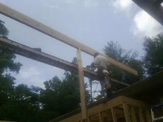 Carpenter setting a ridge beam over a new addition frame — Ice Dam Removal by Roofing Brothers in Maple Lake