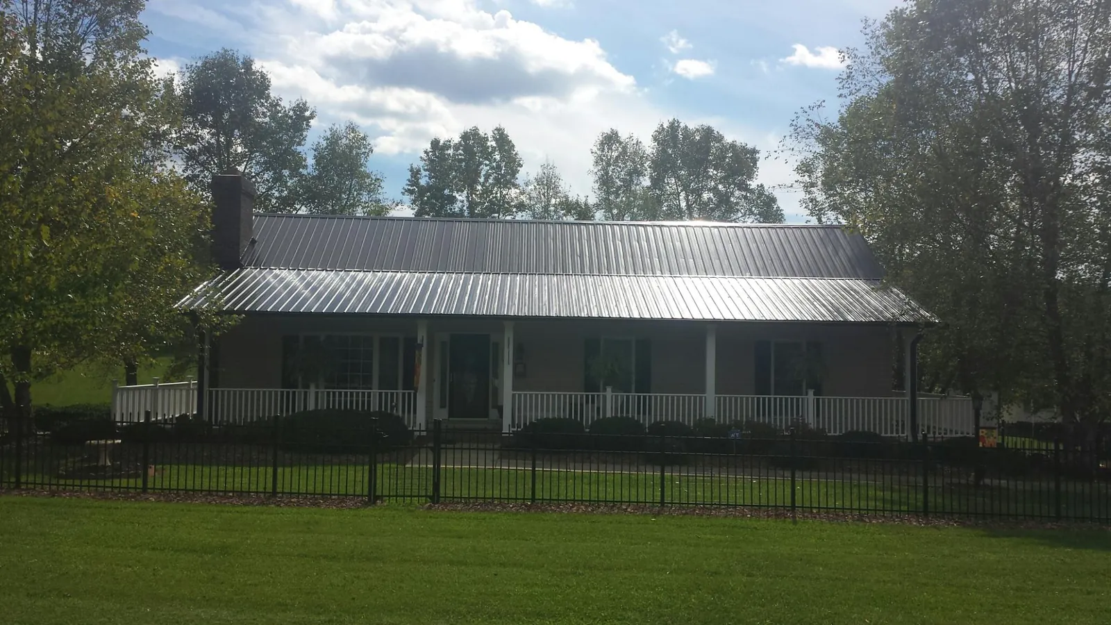 Gray metal roof on a brick ranch with a full width front porch — Gutter Guard Installation work by our crew in Maple Lake
