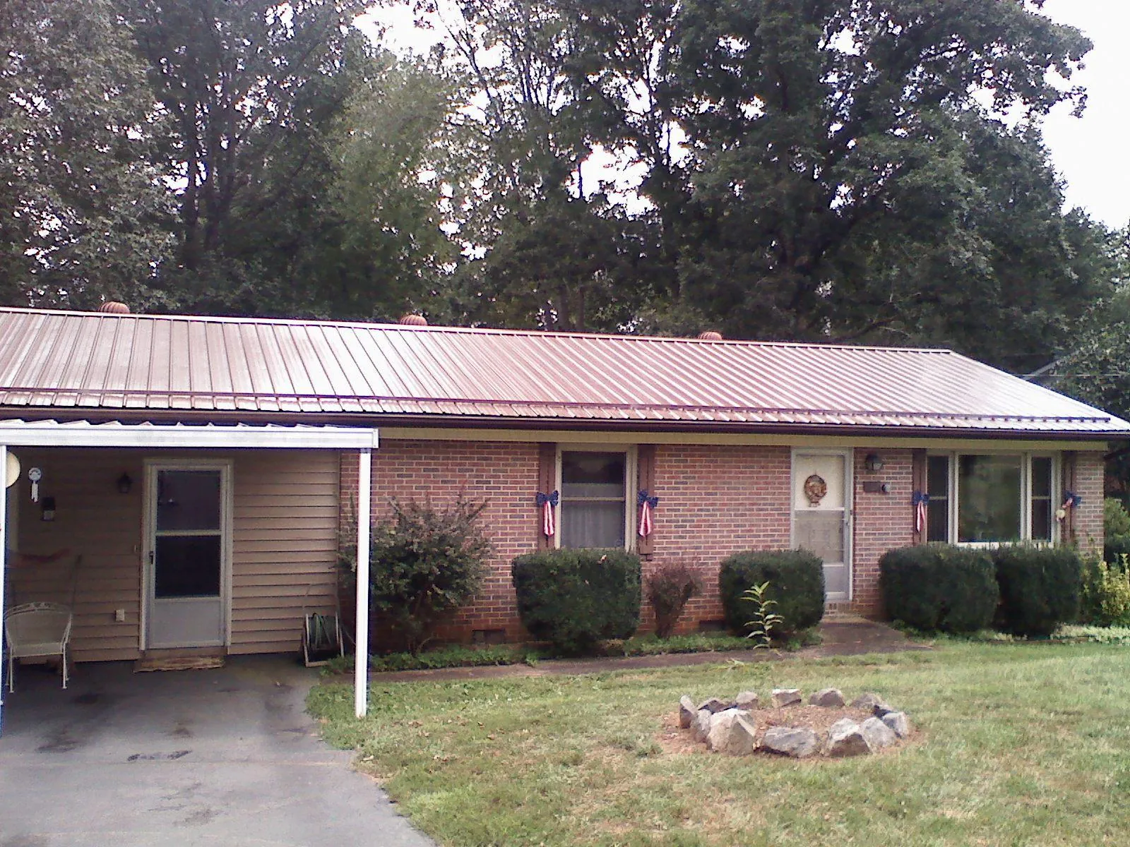 Bronze metal roof and carport on a brick ranch home — Roof Repair work by our crew in Maple Lake