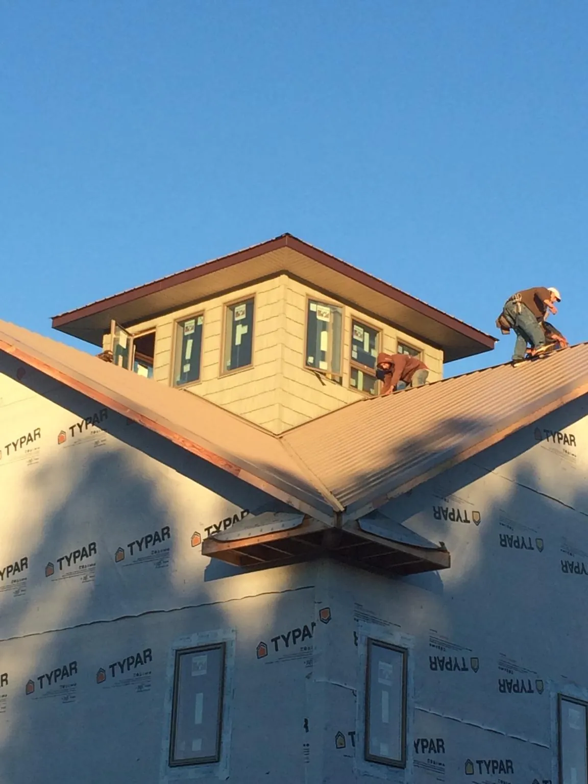 Roofers working around a rooftop cupola on a new metal roof at sunset — Roof Waterproofing in Maple Lake by Roofing Brothers